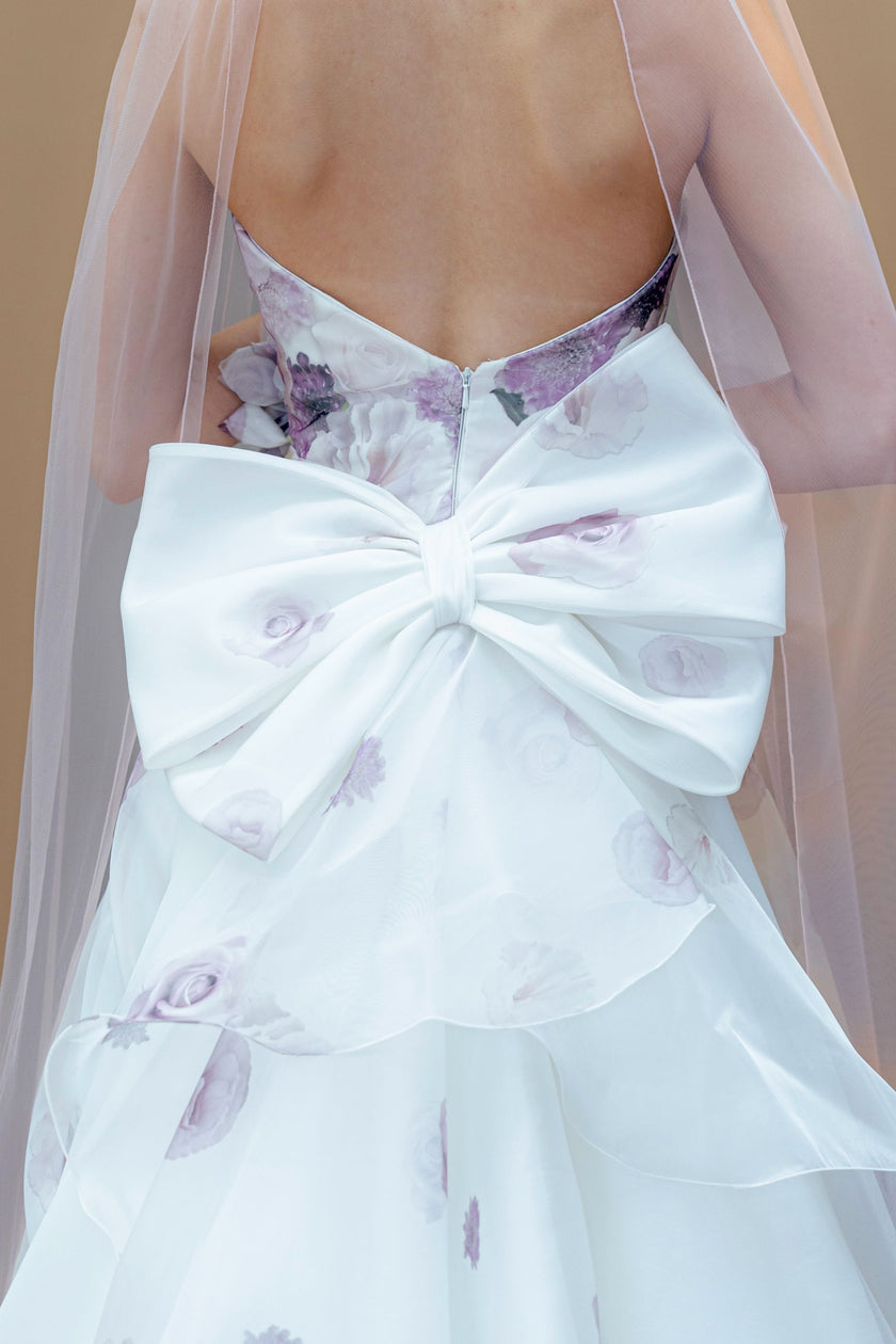 Back of a strapless floral wedding gown with a large bow and cathedral veil.