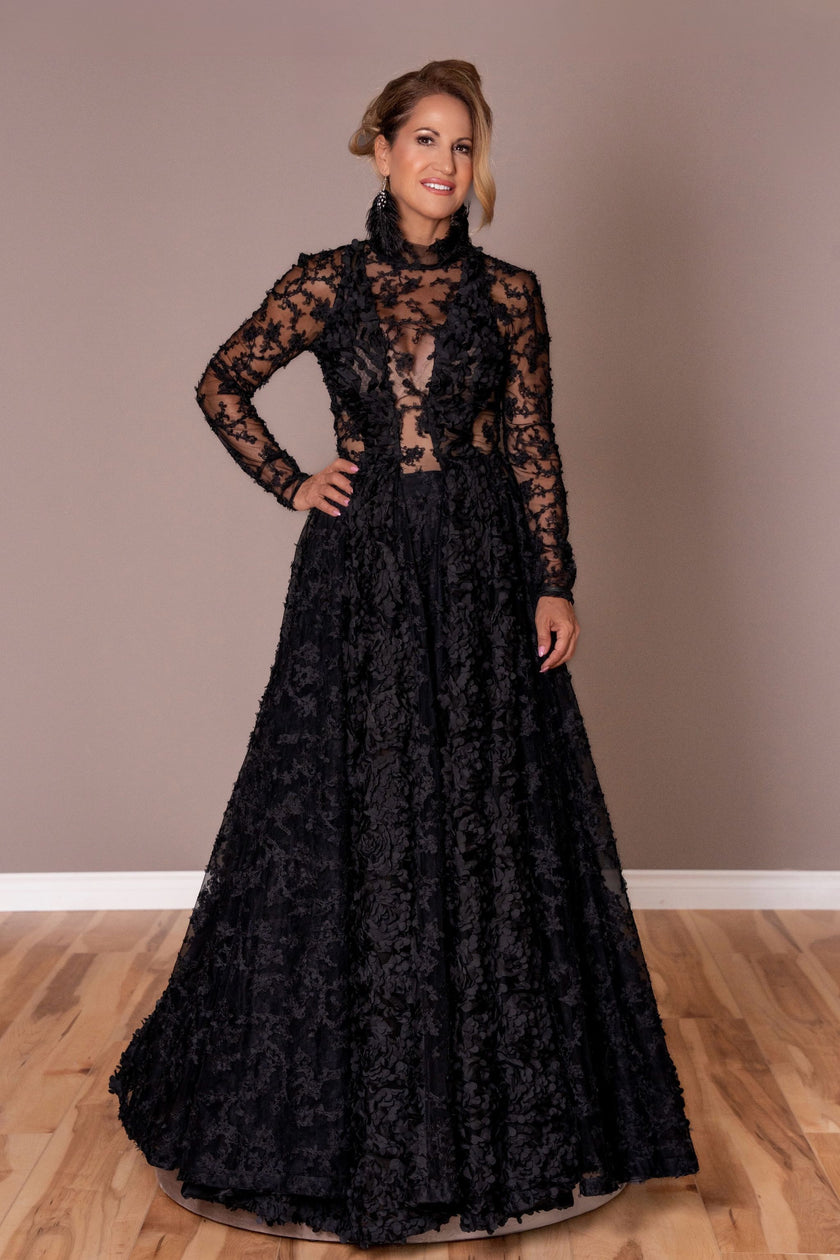 Black couture gown with sheer illusion bodice, floral appliqué, and long sleeves