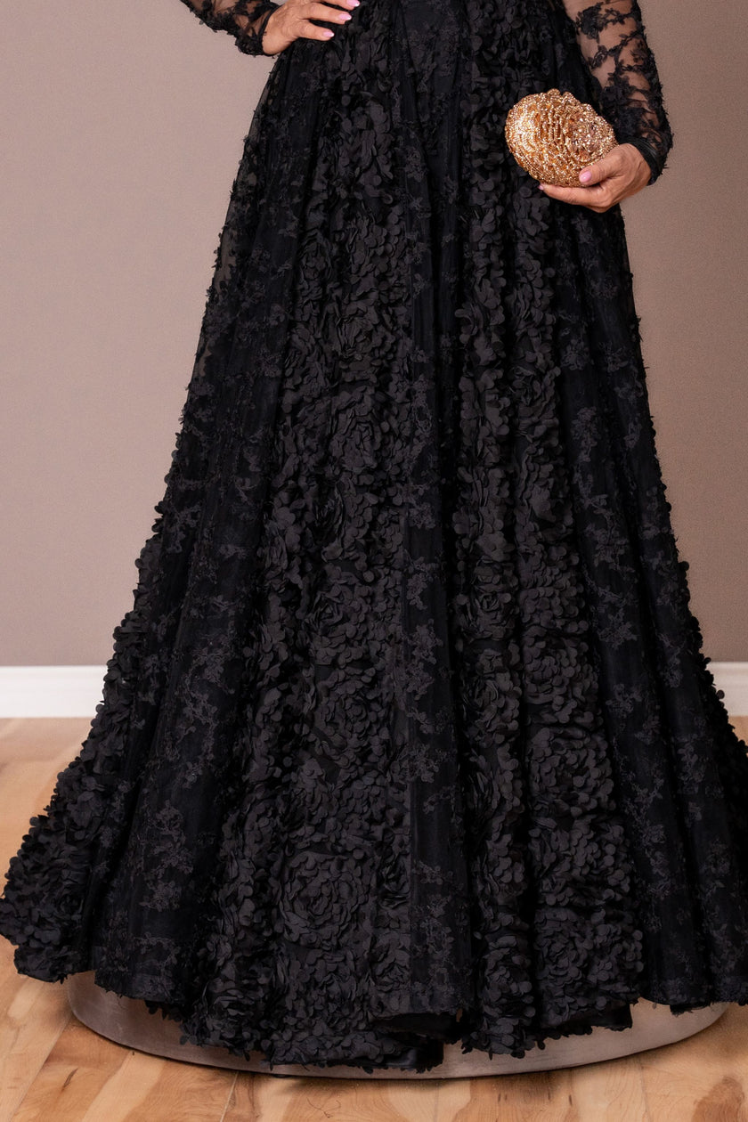 Black lace dress with a hand holding a glittery clutch on a neutral background