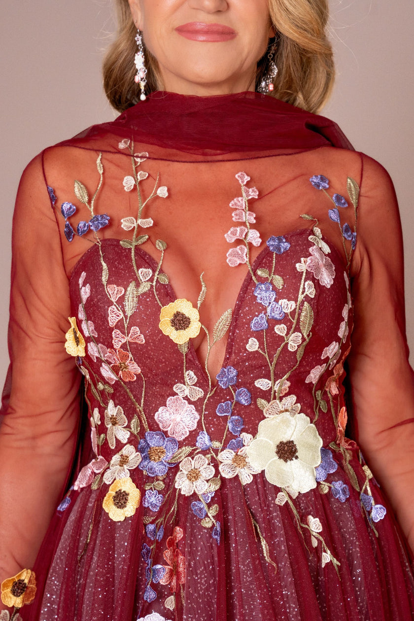 Detailed floral appliqué on the burgundy illusion neckline of a couture evening gown.