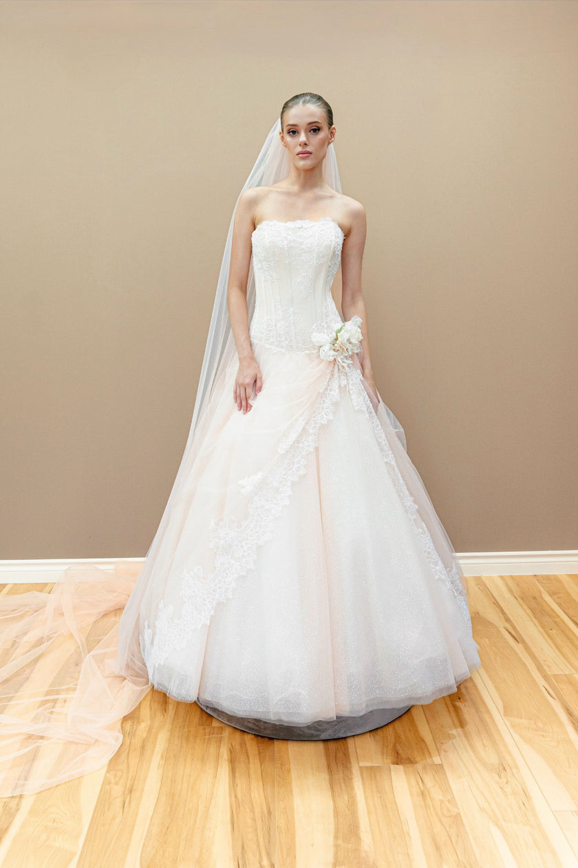 Peach couture wedding gown with a lace corset bodice, embroidered floral appliqué, and a voluminous layered tulle skirt.