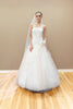 Peach couture wedding gown with a lace corset bodice, embroidered floral appliqué, and a voluminous layered tulle skirt.