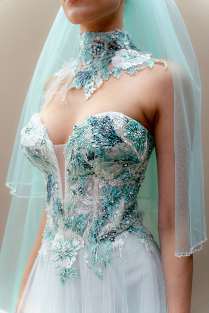 Close-up of aqua wedding gown bodice with embroidered illusion floral appliqué.
