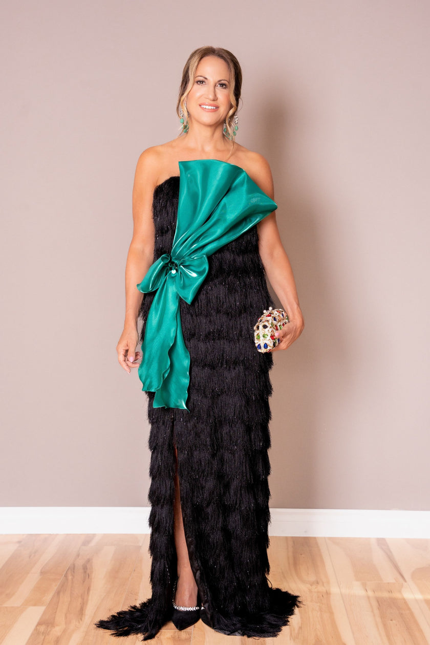 Strapless black fringe evening gown with a large emerald satin bow at the waist.