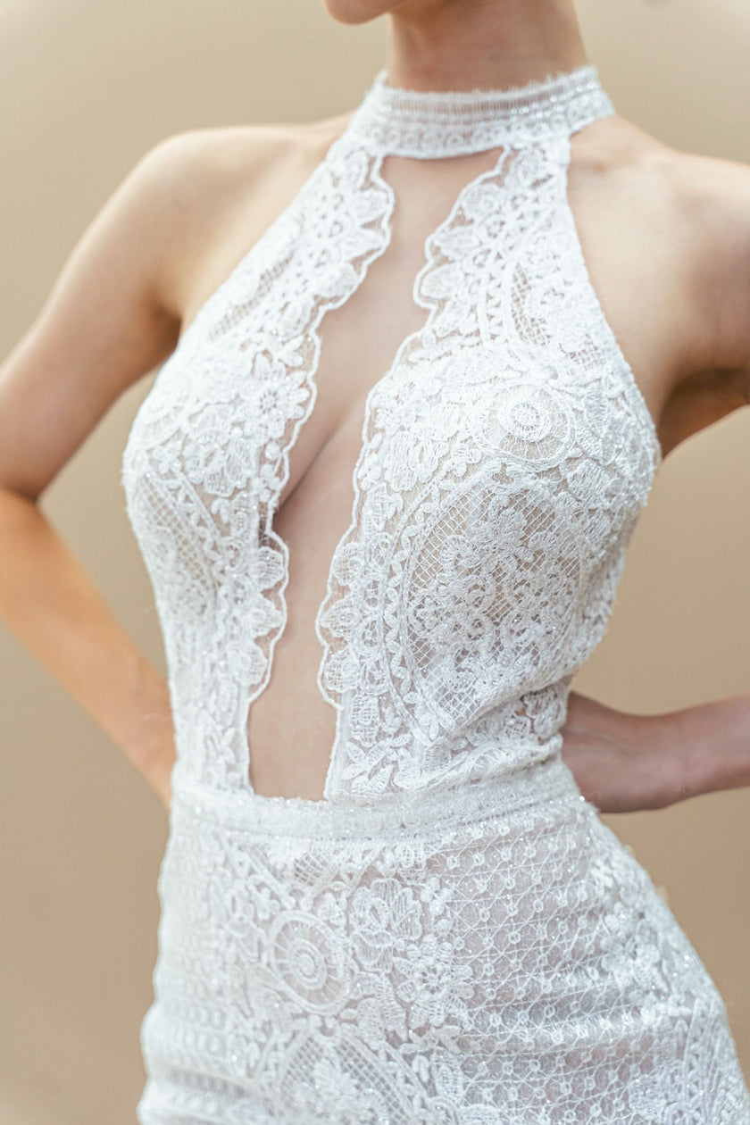 Close-up of the halter neckline and illusion plunge on a modern lace wedding gown.