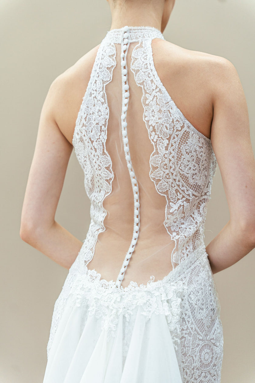 Back view of modern lace wedding gown with open back and detachable overskirt.