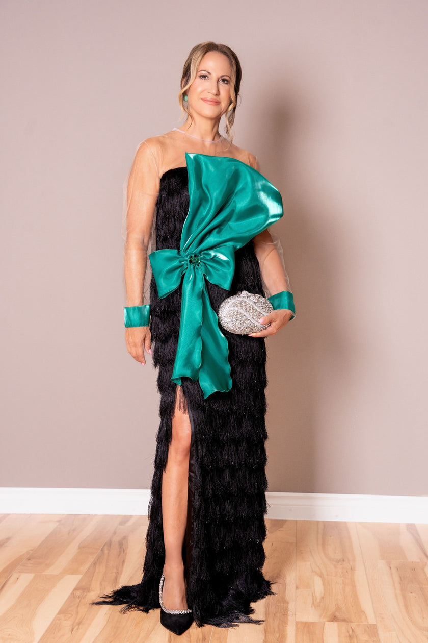 Woman wearing a black evening gown with a large green bow.