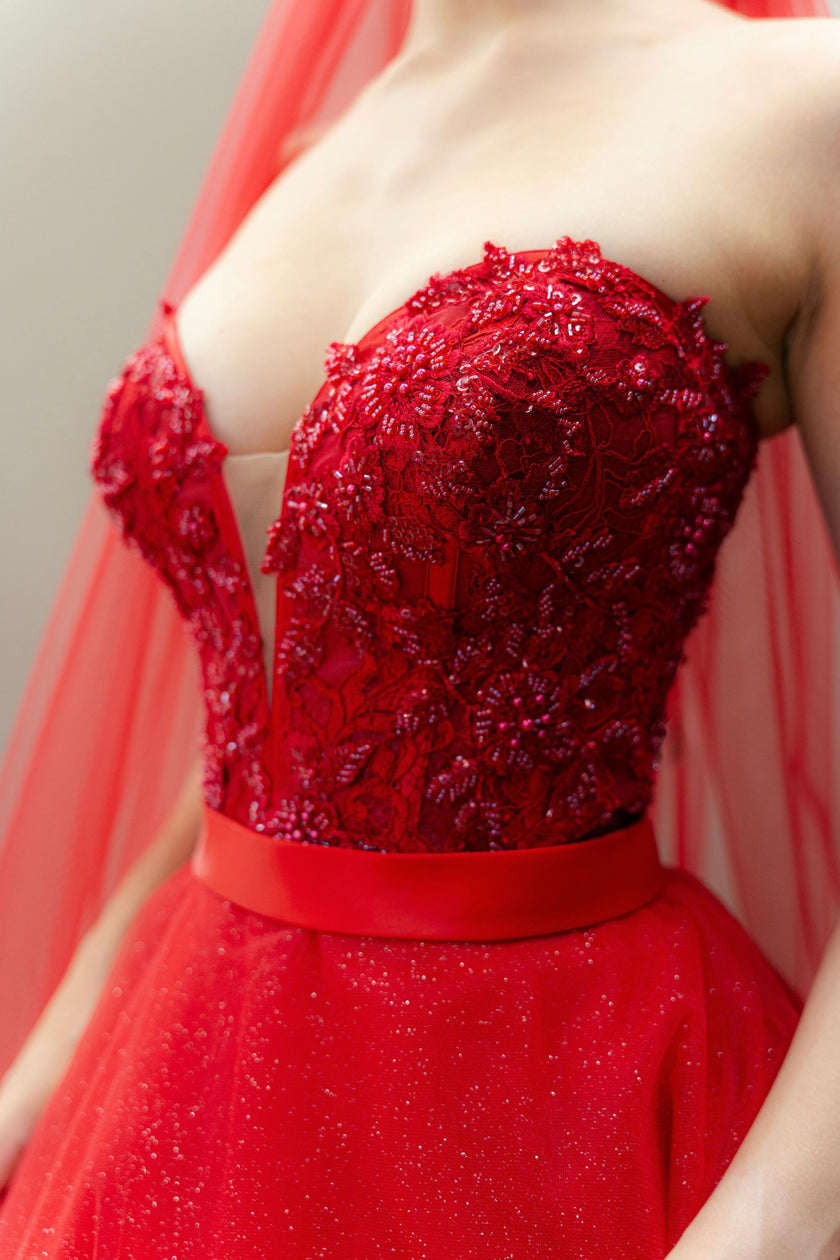 Close-up of the hand-embroidered floral appliqué on the sweetheart illusion bodice of the red ball gown.