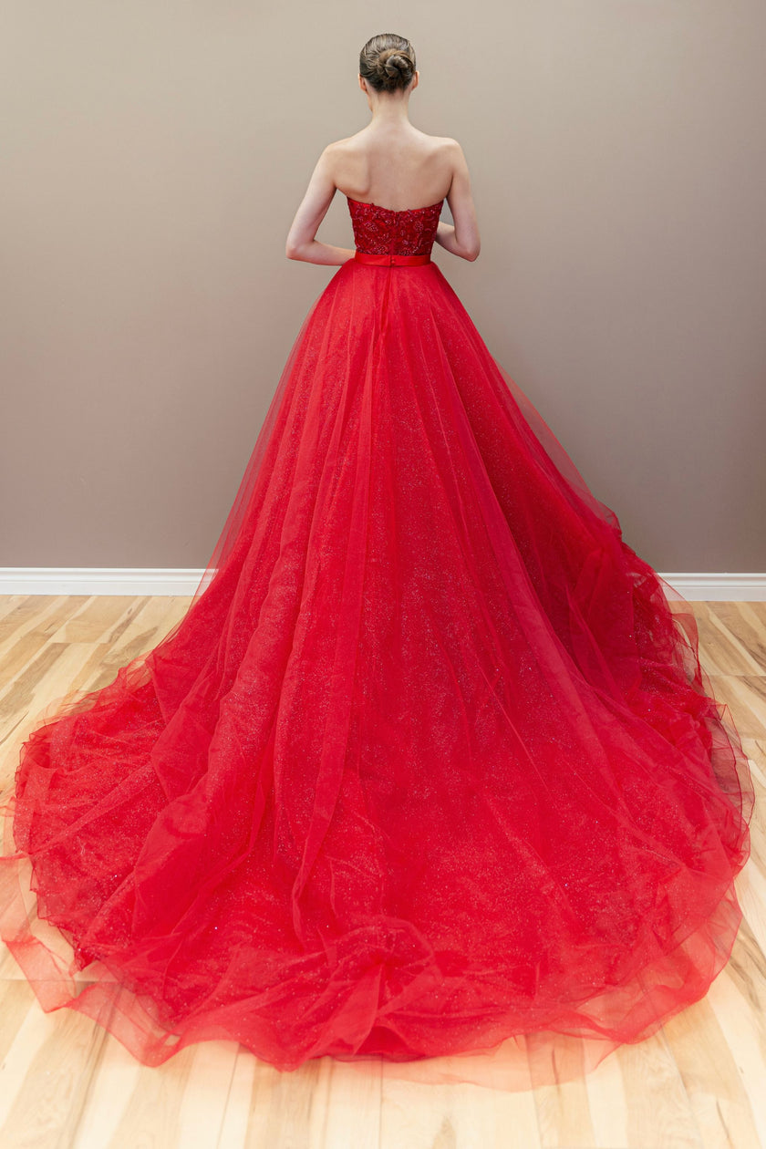Back view of the red couture ball gown, showcasing the full silhouette and matching cathedral veil.
