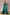 Emerald green off-the-shoulder gown with a structured satin overskirt and shimmering sequin underlay.