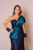 Woman wearing a blue sequin dress with a green draped over-shoulder detail.
