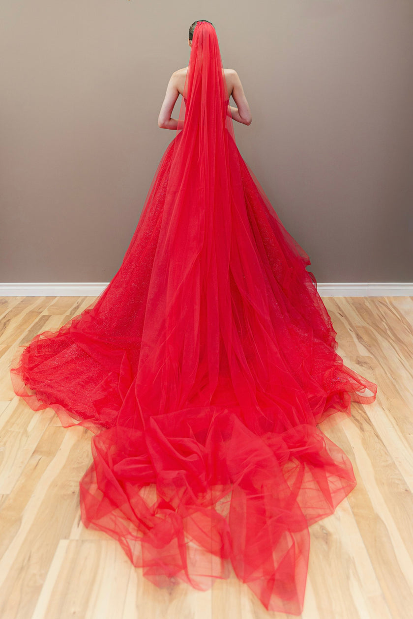 Back of the red embroidered wedding gown showing full skirt and veil.
