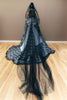 Black lace wedding dress with a long train, featuring a dramatic oversized white bow.