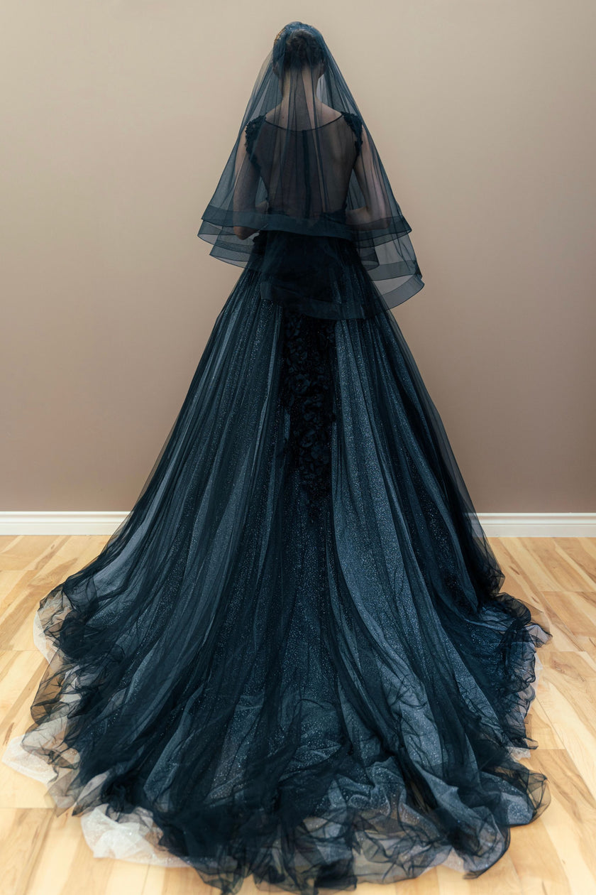 Back view of the embroidered black wedding gown, showcasing the silhouette and long cathedral veil.