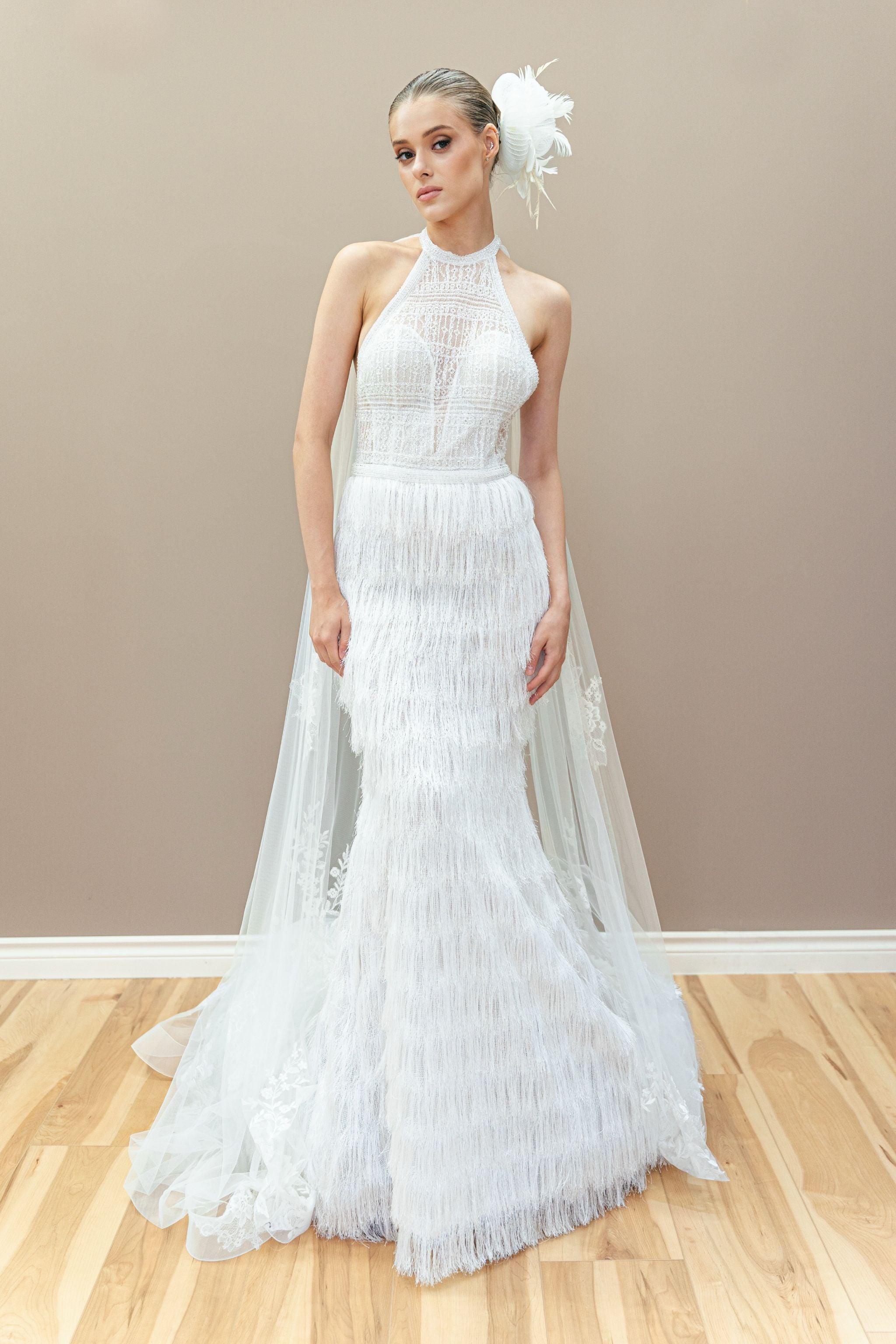 Modern couture wedding gown with a halter neckline, sheer lace bodice, and elegant fringe detailing.
