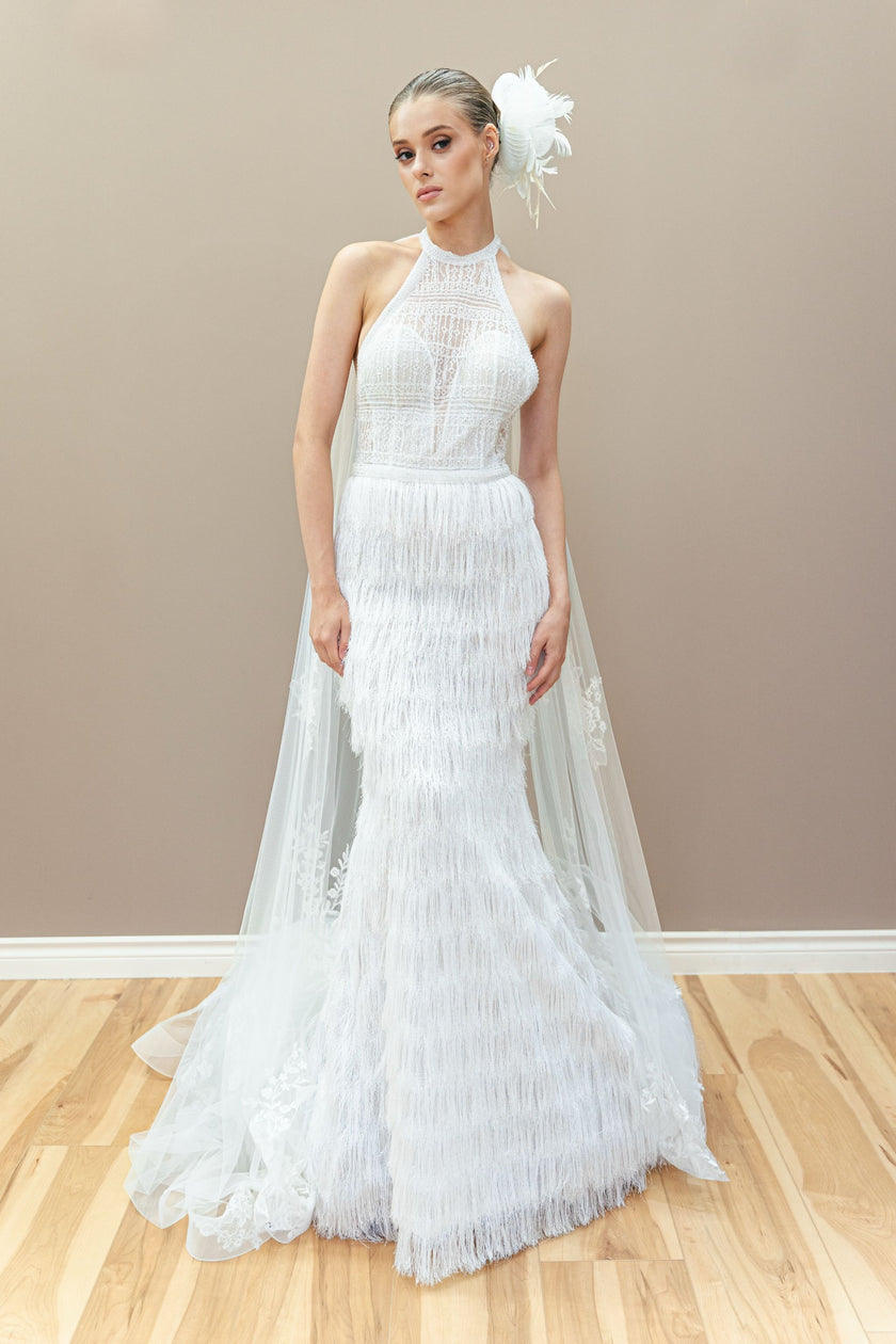 Modern couture wedding gown with a halter neckline, sheer lace bodice, and elegant fringe detailing.