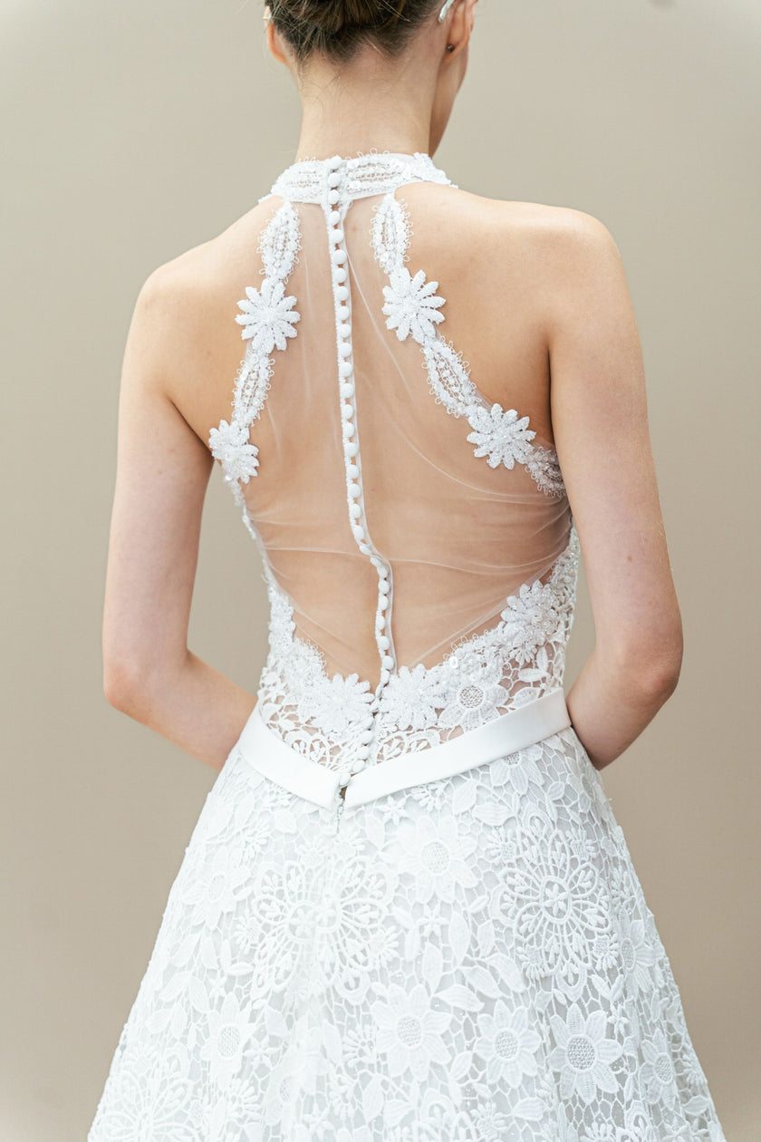 Elegant back view of the halter neck wedding gown with a deep open back, showcasing the lace pattern and A-line shape.