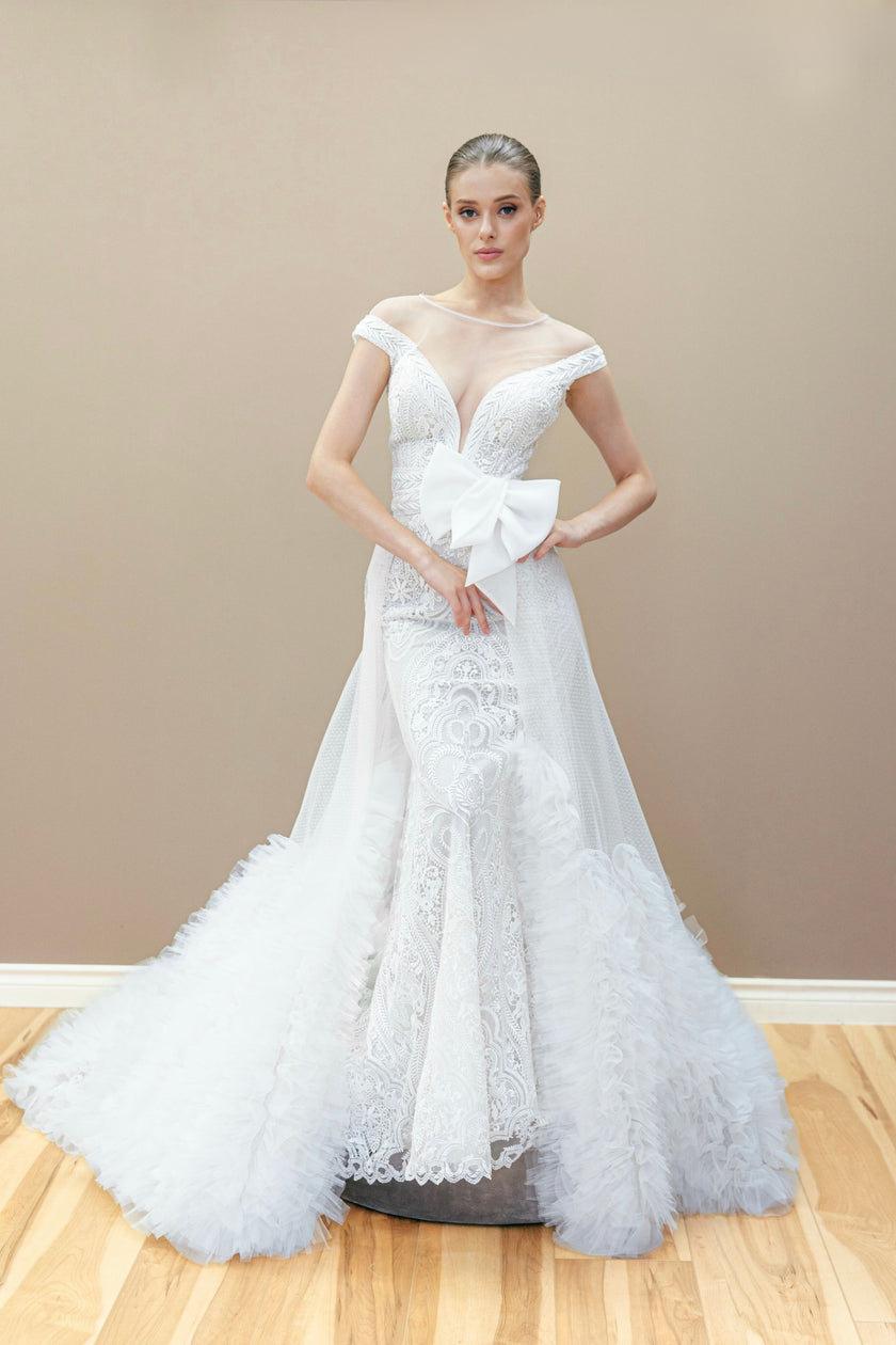 Elegant lace mermaid wedding gown featuring an oversized bow and a dramatic detachable train.