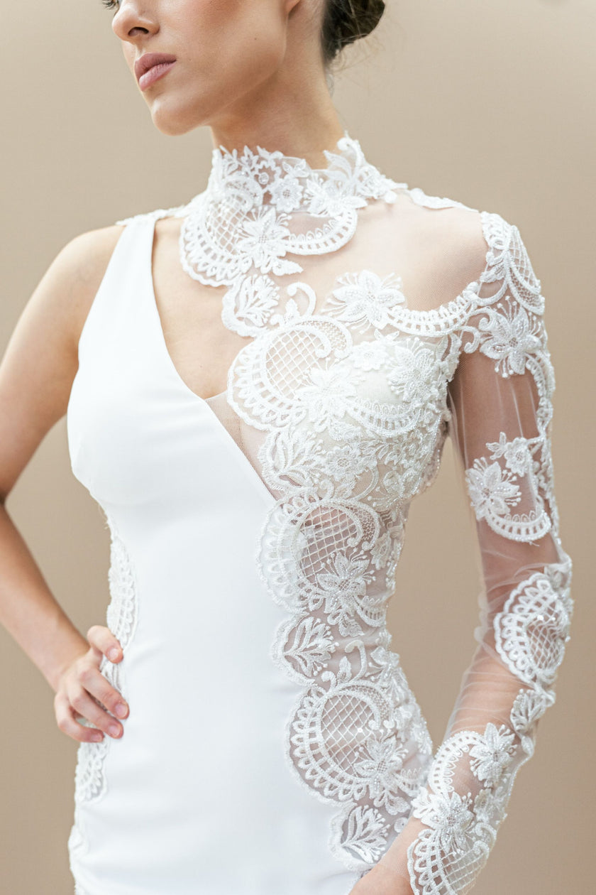 Close-up of the intricate one-shoulder lace design and floral appliqué on the couture wedding gown.