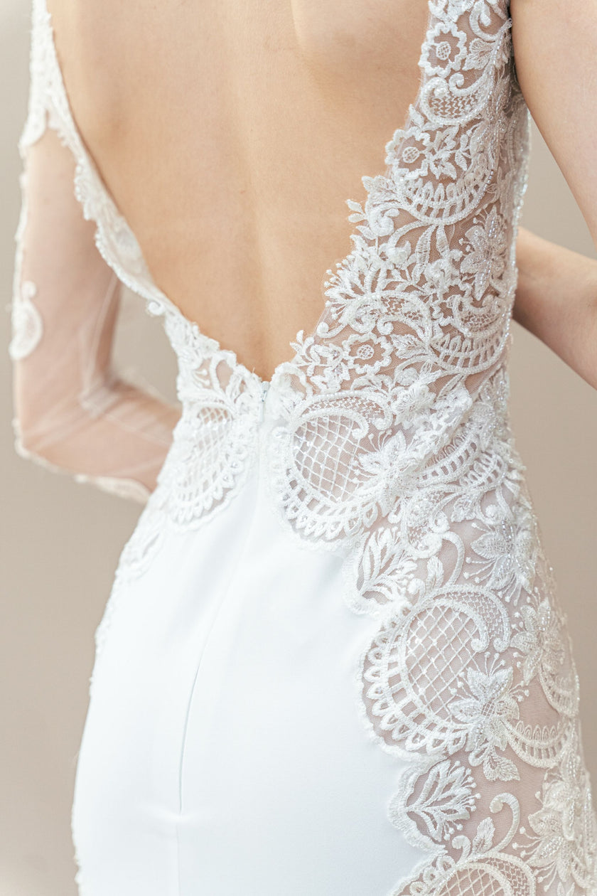 Close-up back view of illusion lace sleeve and floral appliqué on one-shoulder bridal gown.