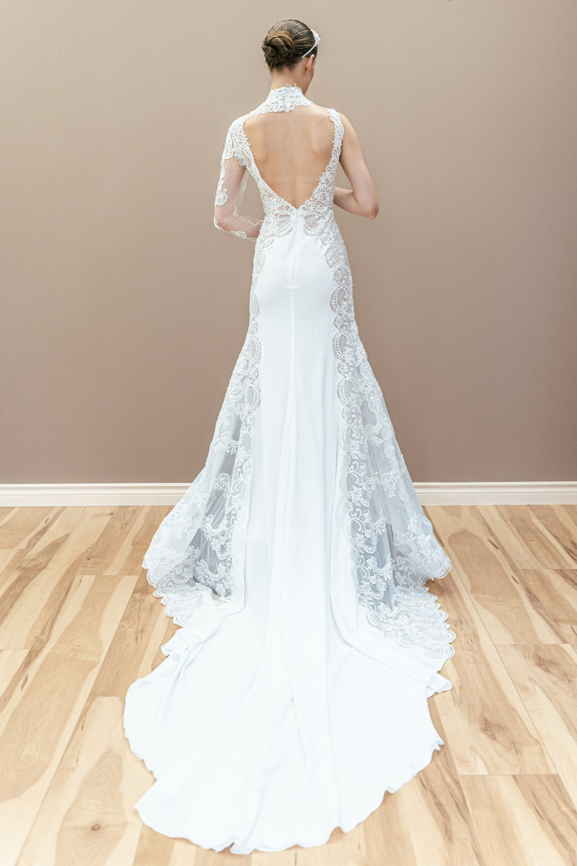Back view of the unique couture wedding gown, showcasing a low back and the elegant lace-trimmed train flowing from the fitted silhouette.
