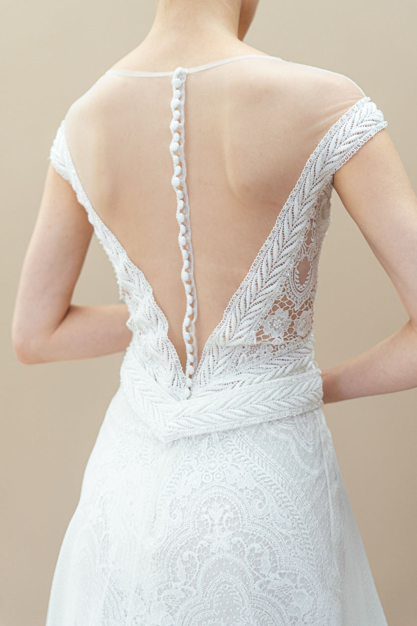 Back view of modern lace wedding gown with illusion neckline and statement oversized bow.